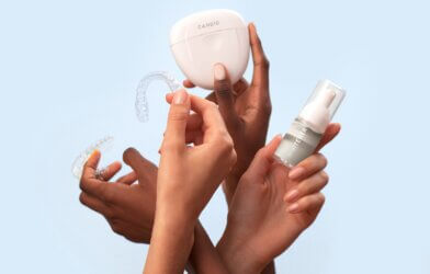 three hands holding teeth whitening products
