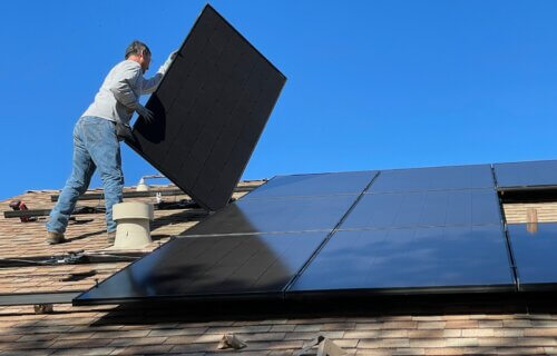 Man installing solar panel on house