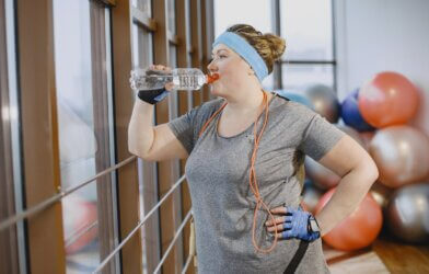 Woman Drinking Water in Gym