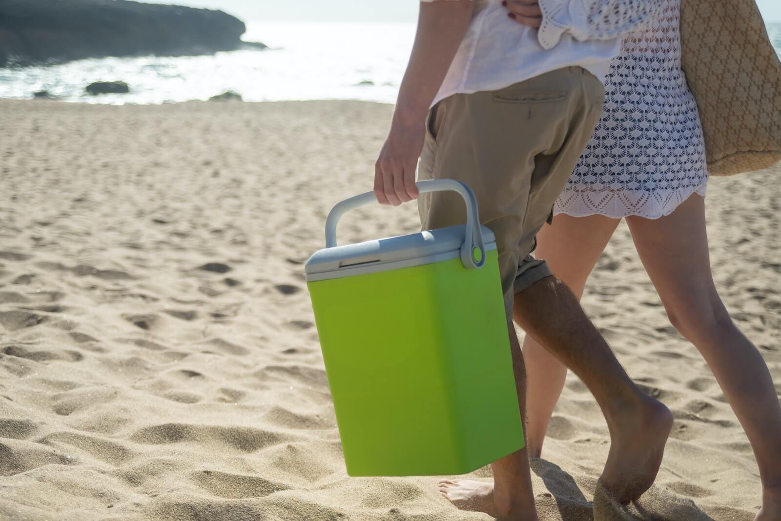 People carrying a cooler on a beach