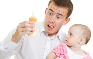 A young father with a baby and bottle of milk