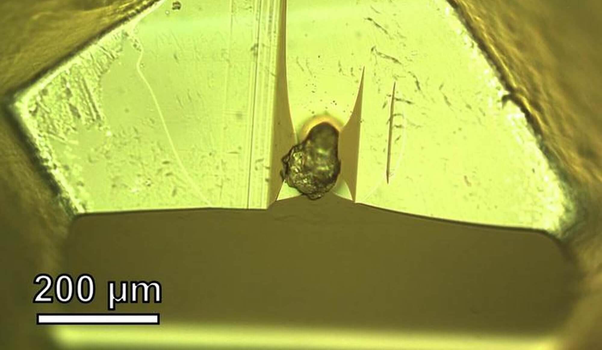 In the lab, researchers embedded the dust particle from asteroid Itokawa in epoxy resin to prepare it for thin sectioning. The scale indicates 200 micrometers, about the width of two or three human hairs placed side by side.