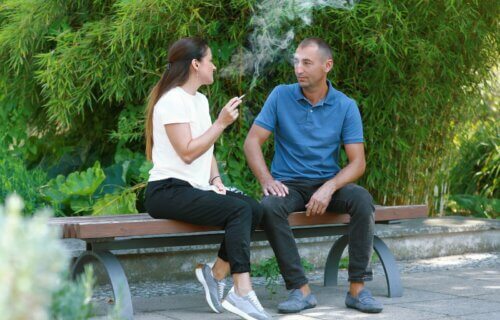man and woman sitting on bench smoking