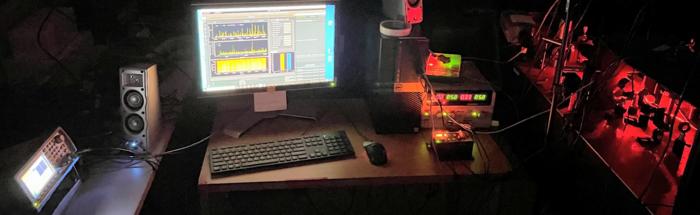 dark with computers on a table and multiples monitors with different analytical results on the screens