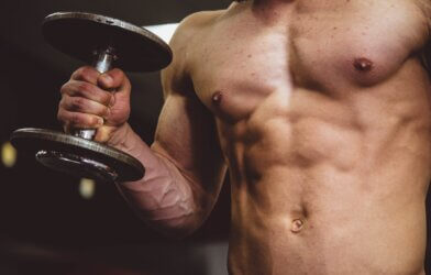 Man with six-pack abs lifting dumbbell weights