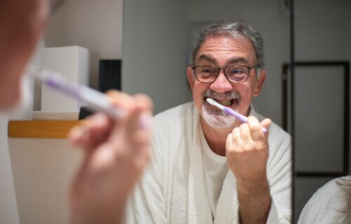 Elderly Man Brushing Teeth in Bathroom