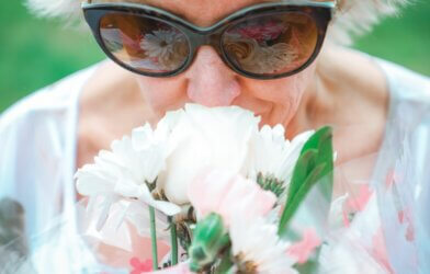 older woman smelling white flower