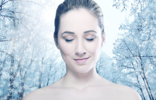 Head and shoulders of young woman with eyes closed over winter forest.