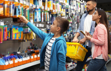 Family with little boy choosing school supplies