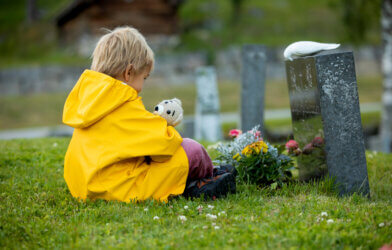 Sad boy mourning in cemetery