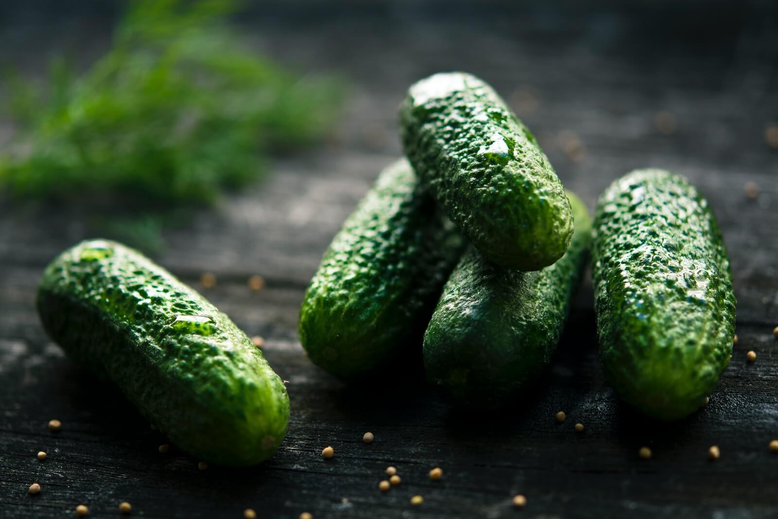 green cucumbers on black wooden table