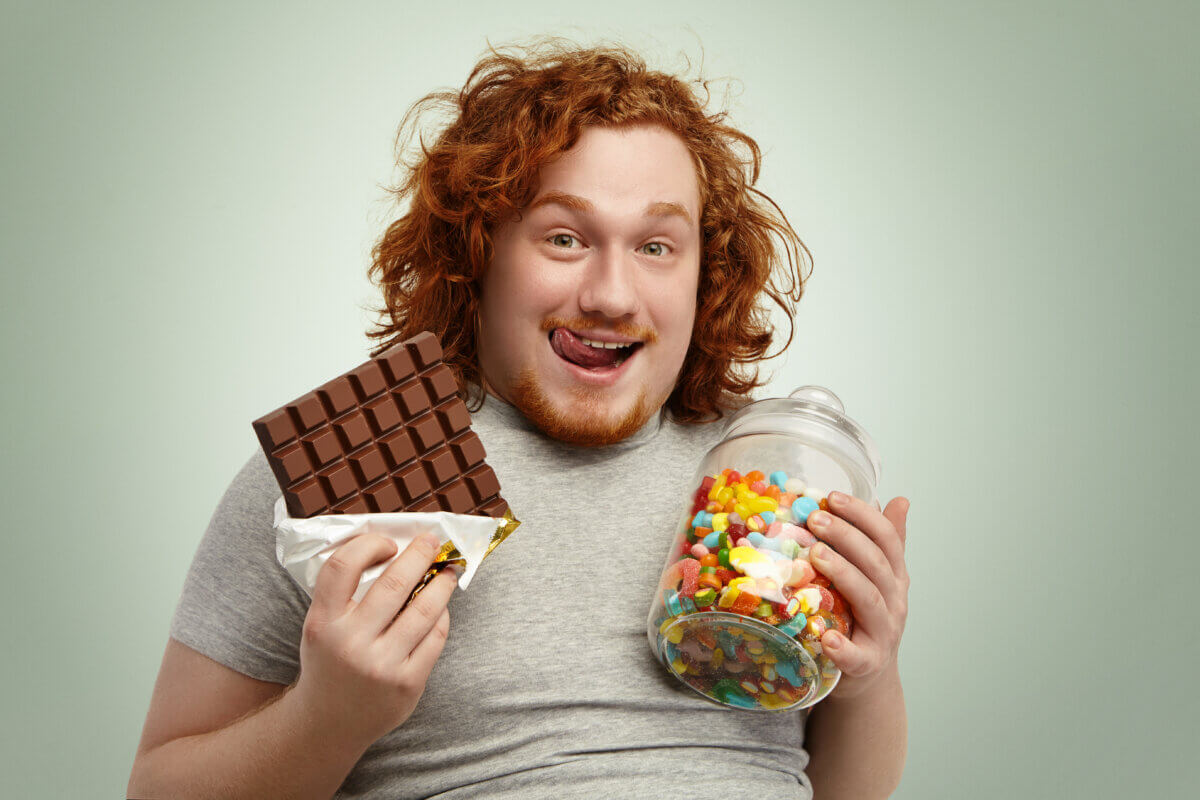 Overweight man eating junk food and sugary snacks
