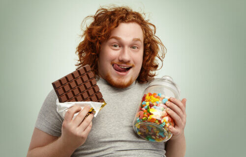 Overweight man eating junk food and sugary snacks