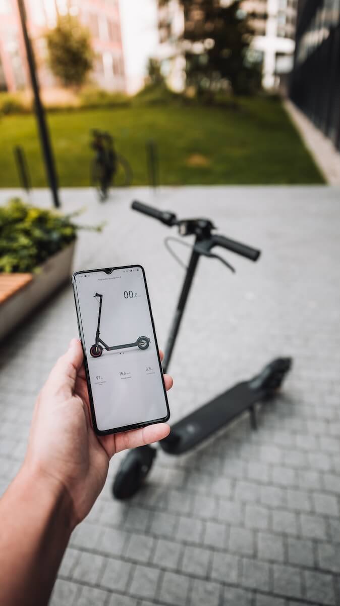 person holding silver iphone 6 in front of an E Scooter Photo by Martin Katler photo on Unsplash