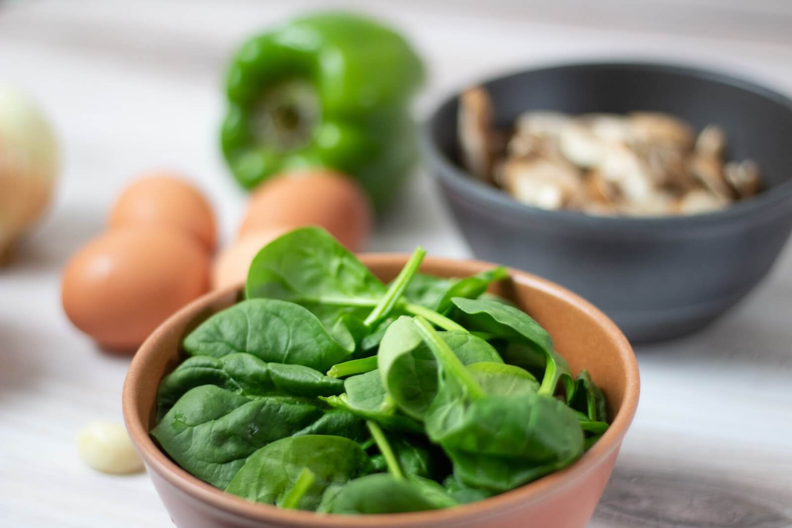 Bowl of spinach in front of other ingredients