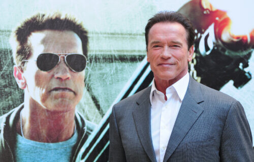 Arnold Schwarzenegger standing in front of a poster for "The Last Stand" in 2013