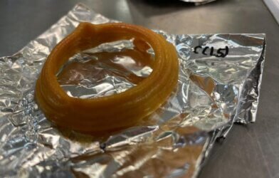 3d printed brown edible calamari ring sits on top of a sheet of foil.