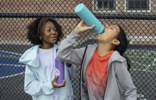 Girls drinking water on a tennis court