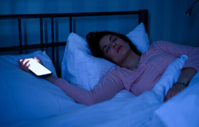 woman sleeping while holding still active smartphone