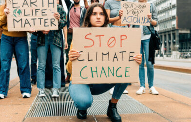 worried young woman holding up a stop climate change sign