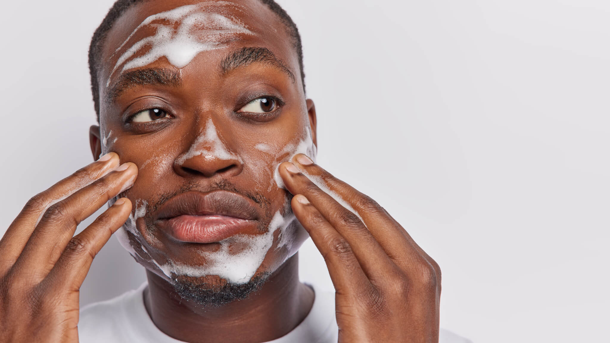 Black man cleansing and washing his face with soap