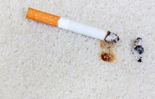 A lit cigarette on carpeting