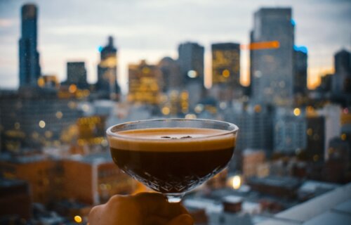 Someone holding an espresso martini at a rooftop restaurant