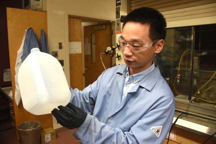 Guoliang “Greg” Liu holds a common water jug in his lab at Hahn Hall South. 