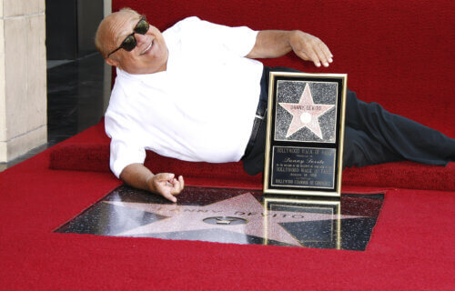 Danny DeVito posing with his star on the Hollywood Walk of Fame