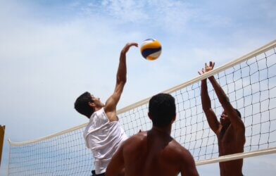 A man spiking a volleyball over a net