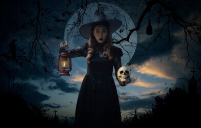 Halloween witch holding ancient lamp and skull