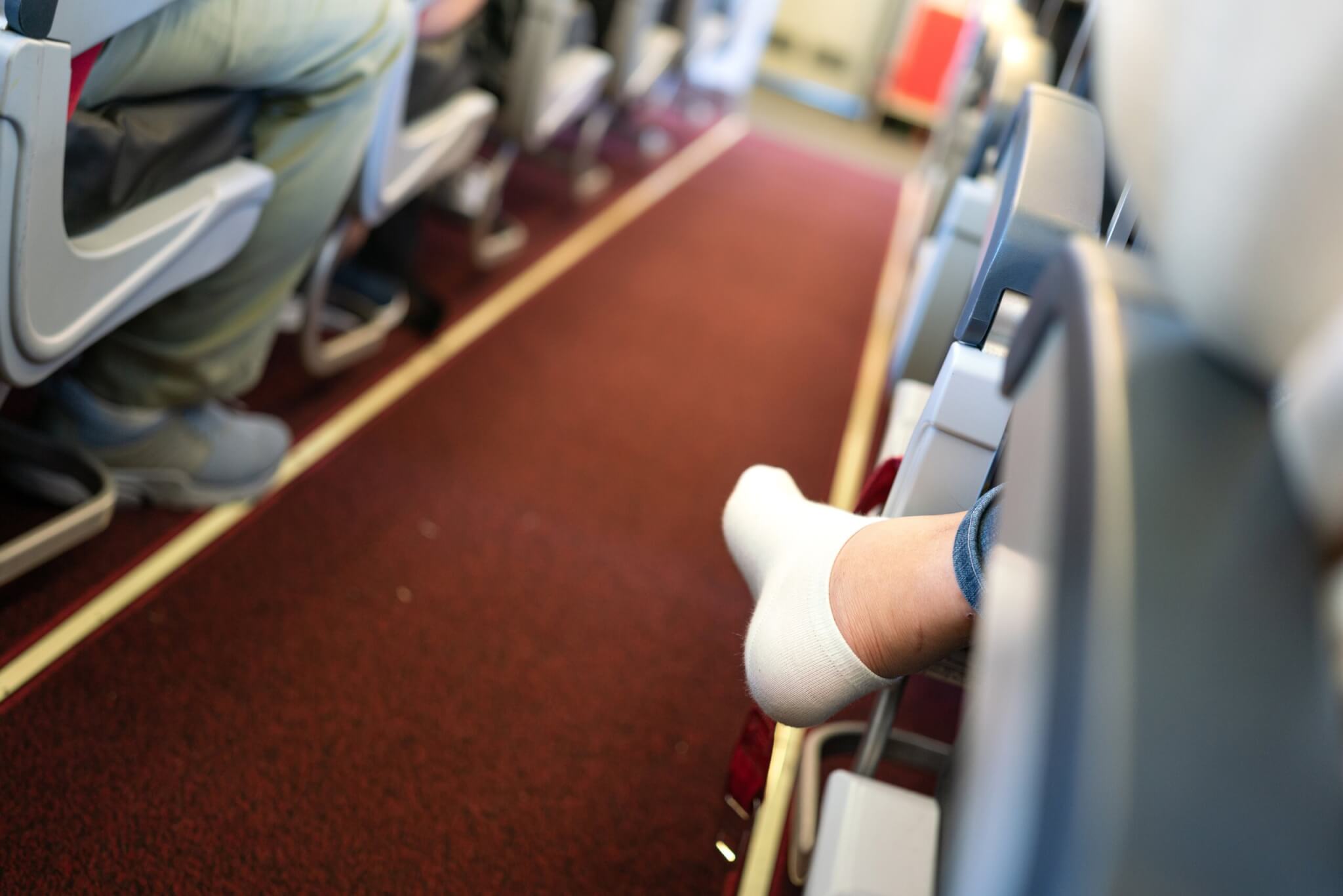 Airplane passenger with shoes off and socks in the aisle during the flight.