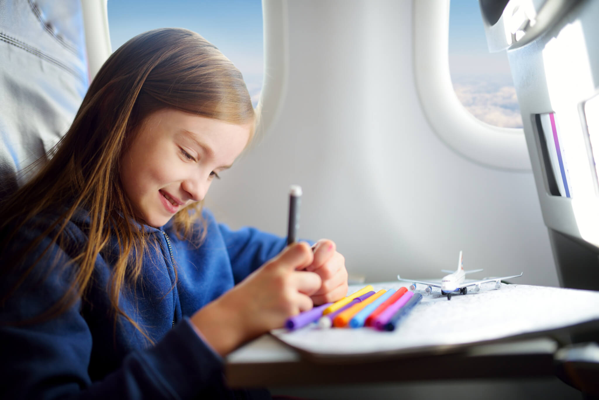 Young girl coloring while on an airplane flight.