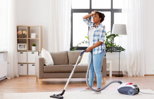 Woman vacuuming the floor and getting tired