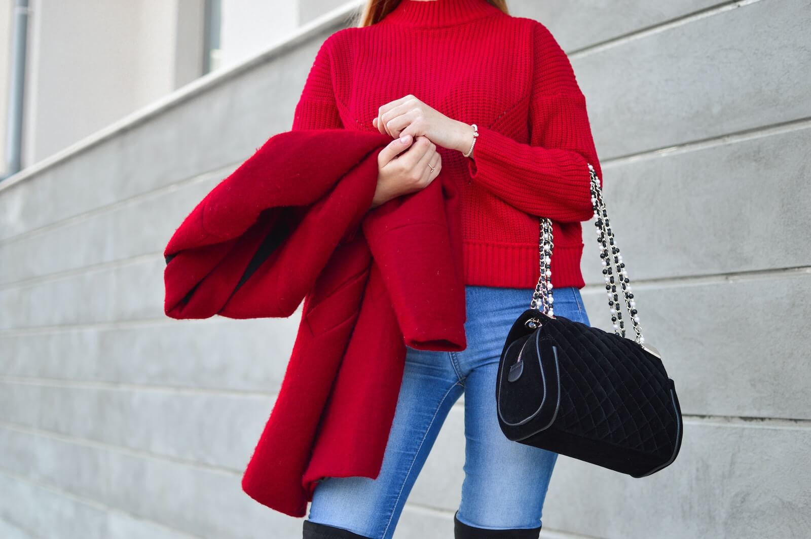 A woman in a red sweater holding a red coat