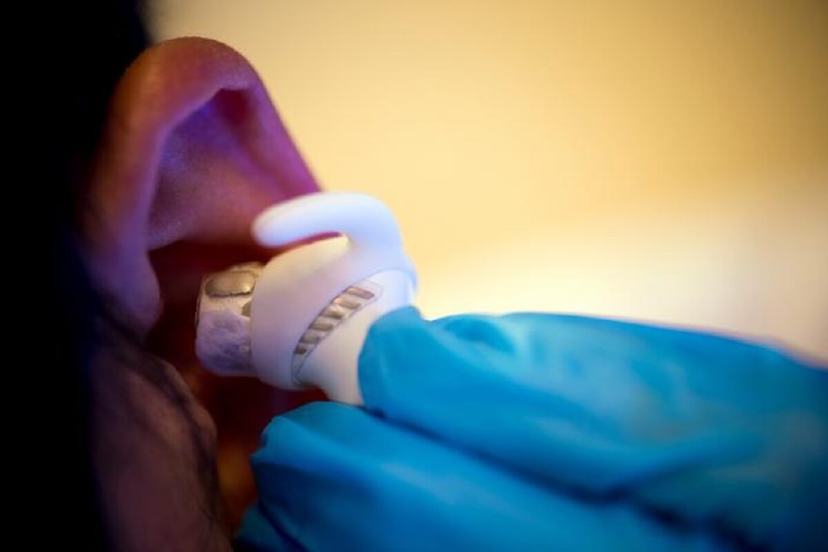 white earbuds being inserted into an ear canal