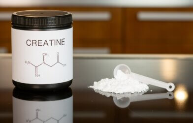 a bottle of creatine next to a spoon