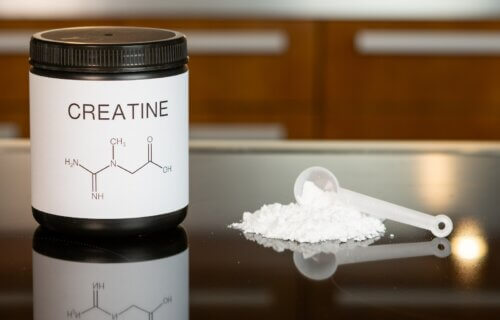 a bottle of creatine next to a spoon