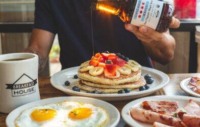 a man is pouring syrup on a stack of pancakes