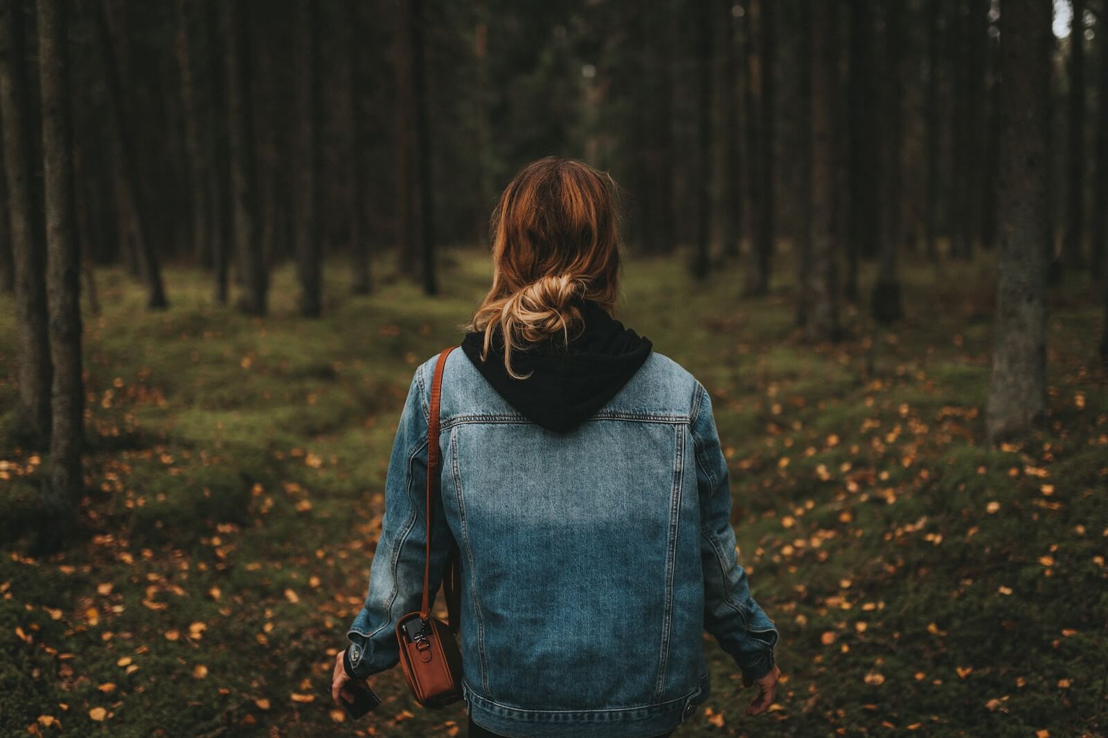 A woman in a jean jacket on a fall trail