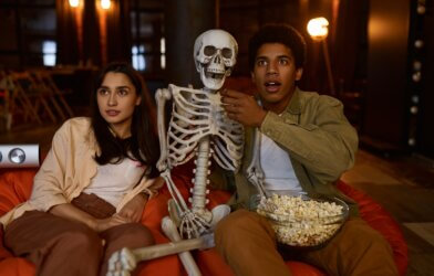 A couple watching a Halloween movie with a skeleton