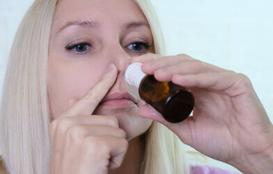woman holds a nasal spray to her nose