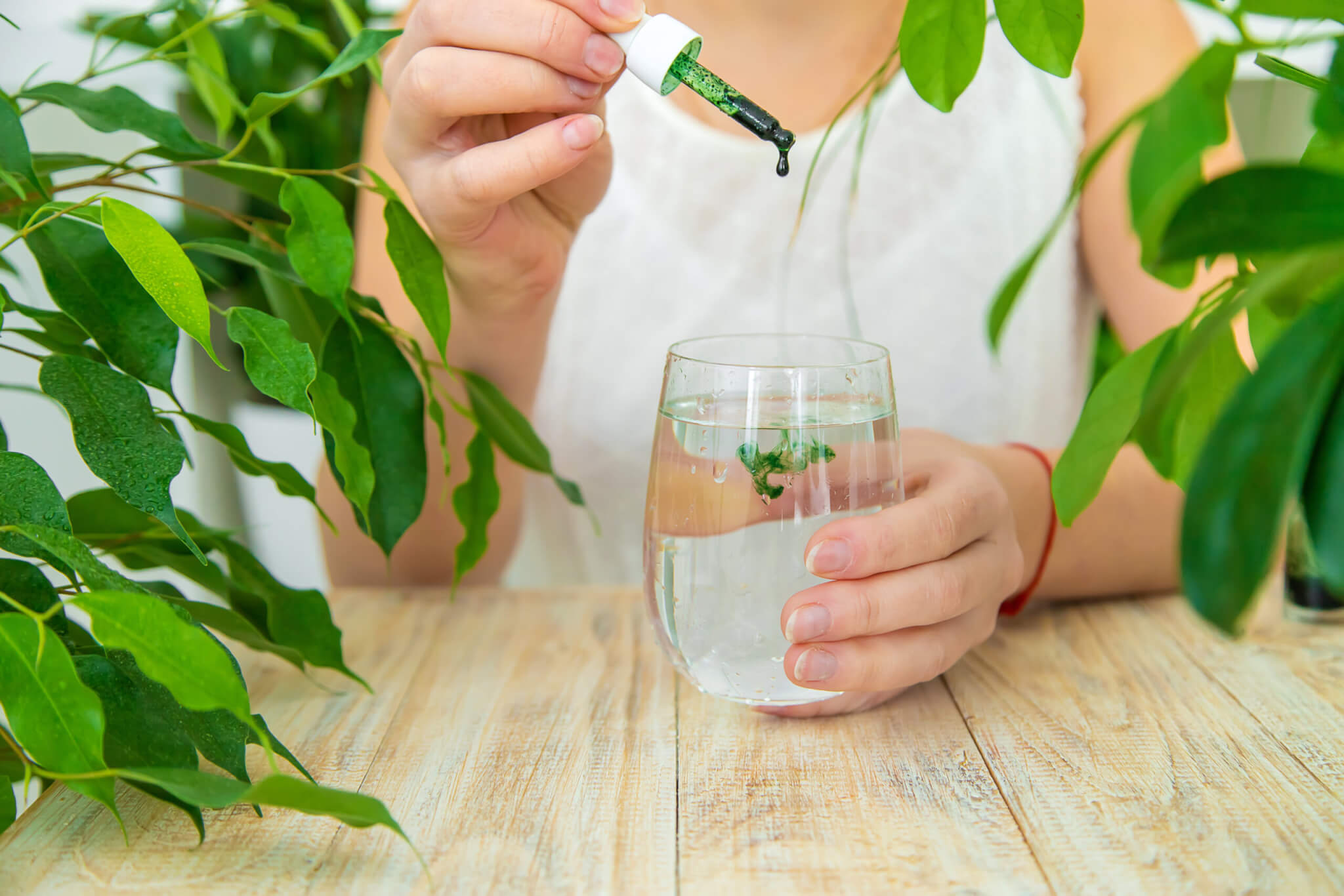 Woman dripping chlorophyll supplement into a glass of water