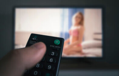 remote control in a man's hand watching erotic movie