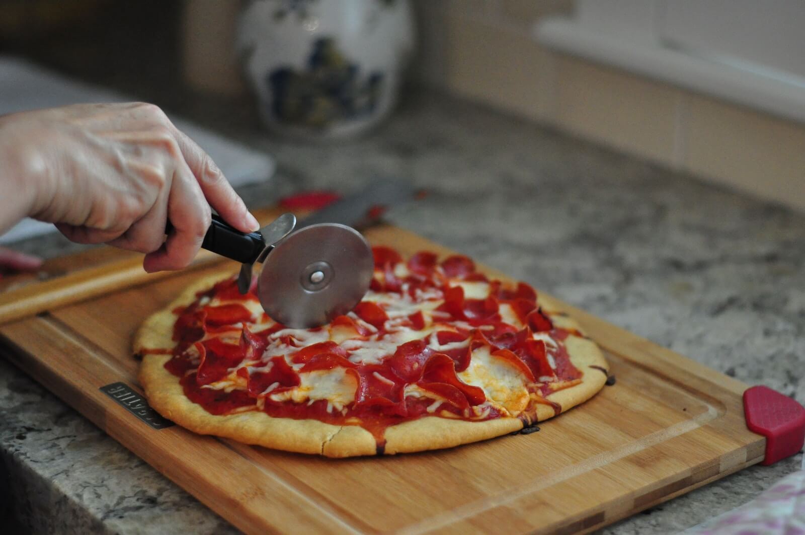 person slicing pizza