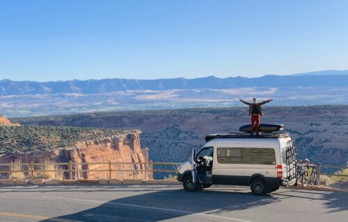 A man standing on top of a converted sprinter van