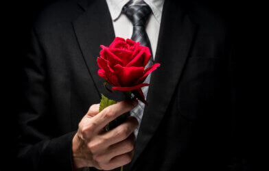 A man in a suit holding a rose