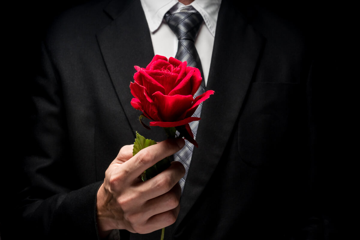 A man in a suit holding a rose