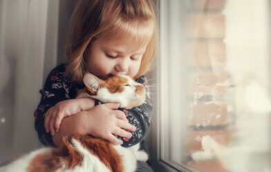 A little girl hugging a cat