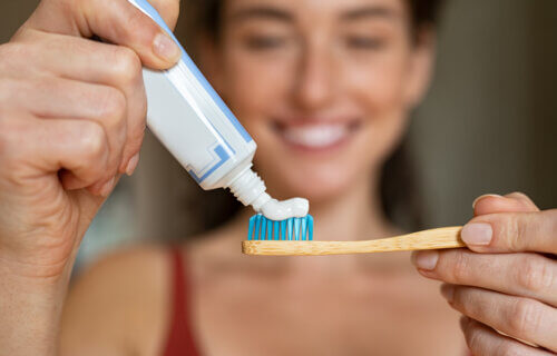 A woman applying toothpaste to her toothbrush